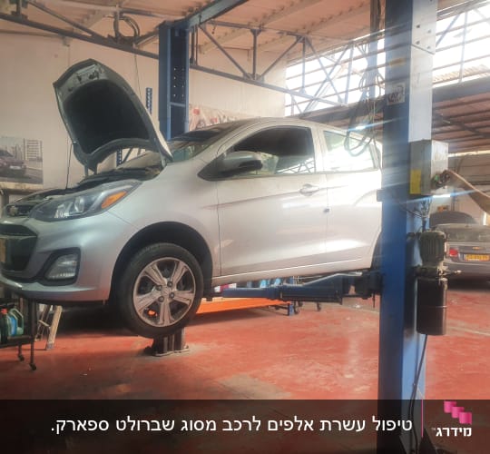 רכב על מעלית במוסך עם מכסה מנוע פתוח